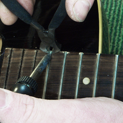 removing old frets with plier and soldering iron